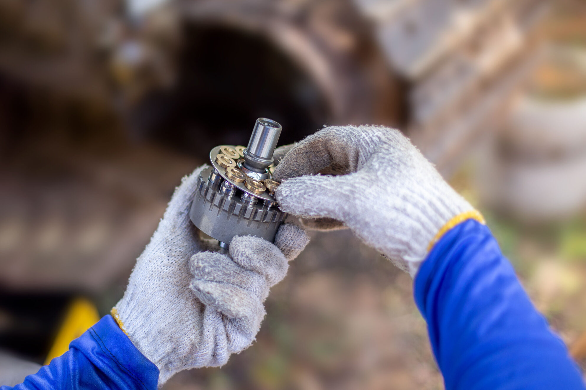 A service technician repairs a damaged hydraulic pump. Professio